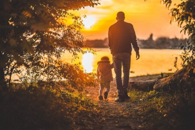 father and child walking in a sunset