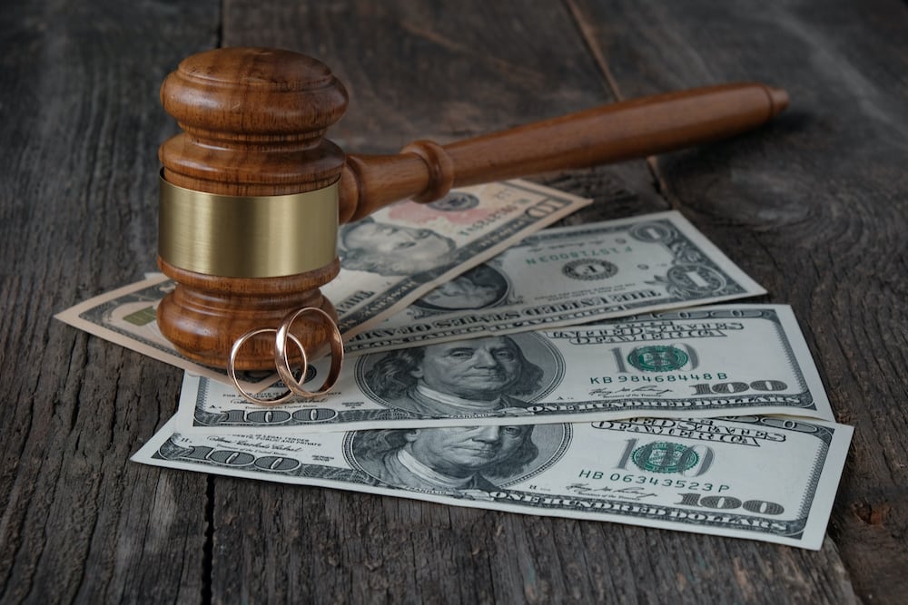 a gavel with two wedding rings on top of money