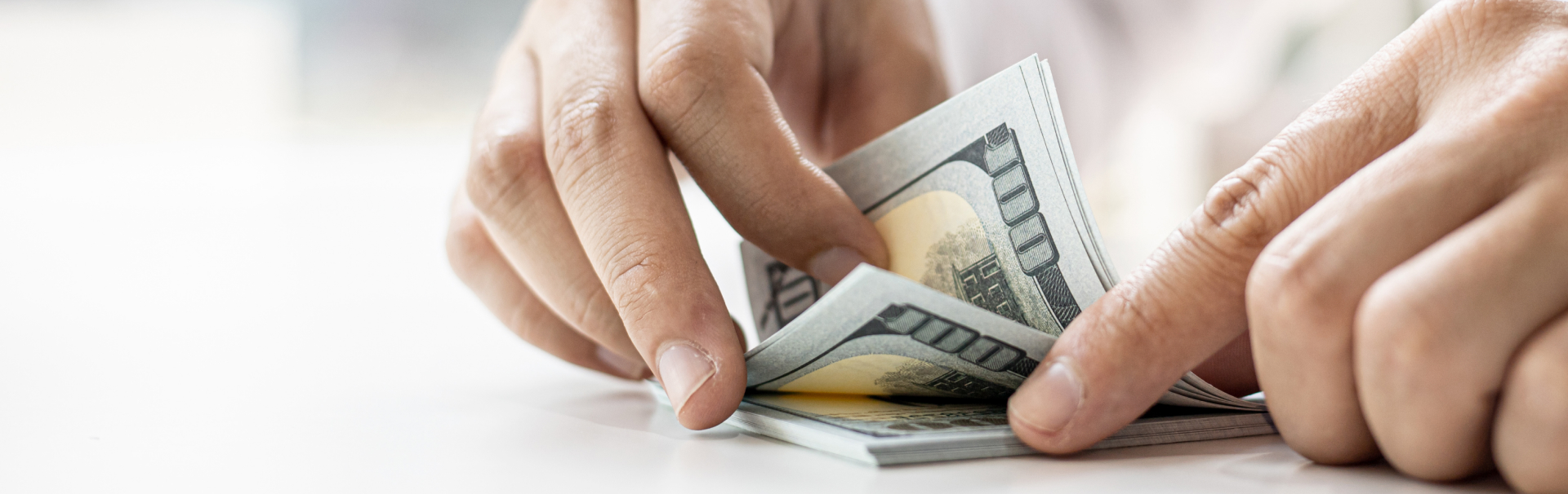 A businessman counting his dollar bills on a white table