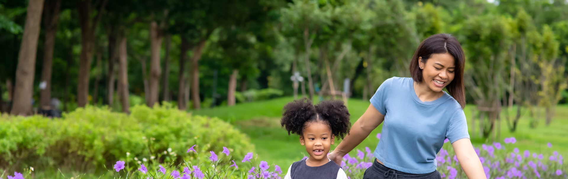 Happy mixed race family mother with little daughter holding hands and walking together in the garden