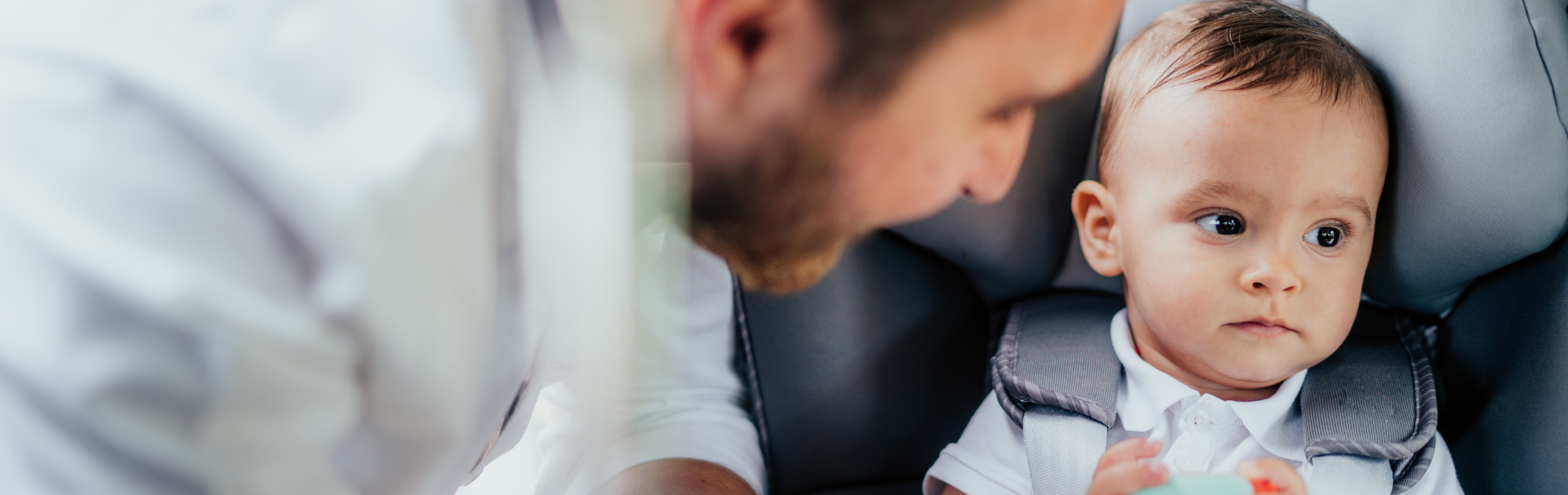 Portrait of caring young father and baby boy enjoying car transportation with child seat